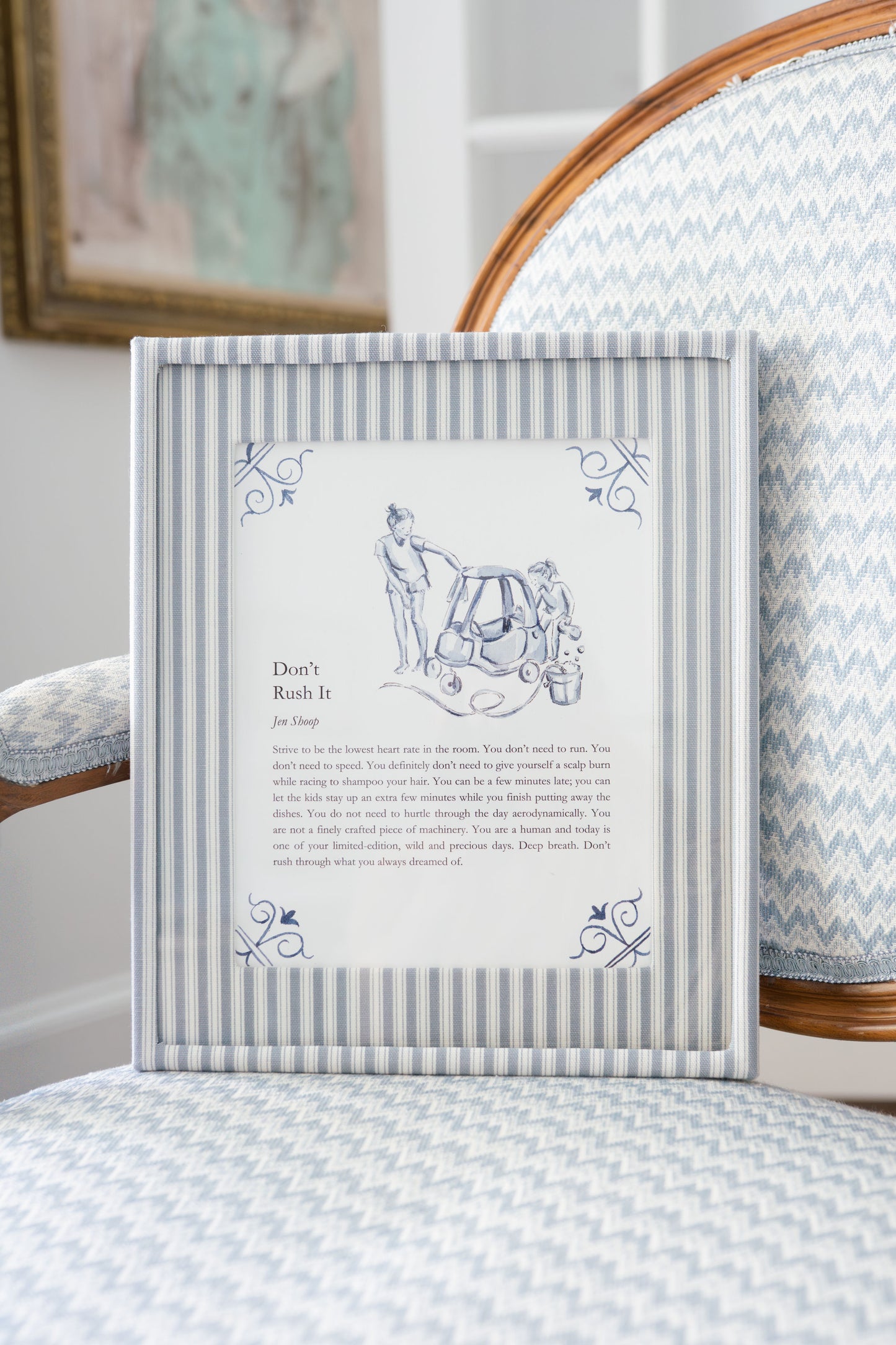 ‘Don’t Rush It’ art print framed in blue striped frame on chair, blue-and-white decor.