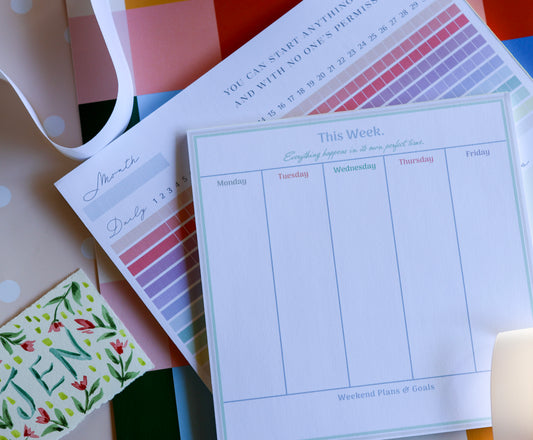 Flat lay of The Gift Set — Magpie x Mamey habit tracker and weekly planner with warm checkered background.