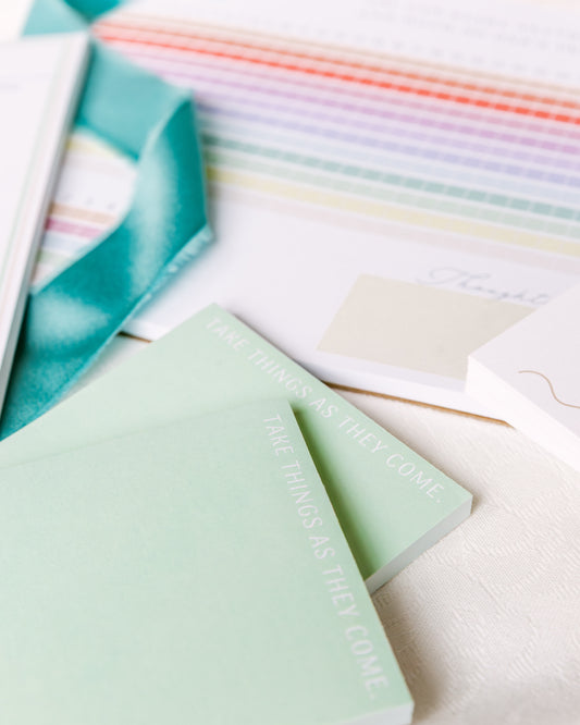 Magpie x Mamey colorblocked notepad with “Take Things As They Come” text, styled with ribbon and habit tracker