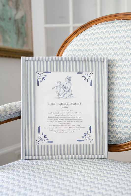‘Notes to Self on Motherhood’ art print framed in blue striped frame on chair, blue-and-white decor.