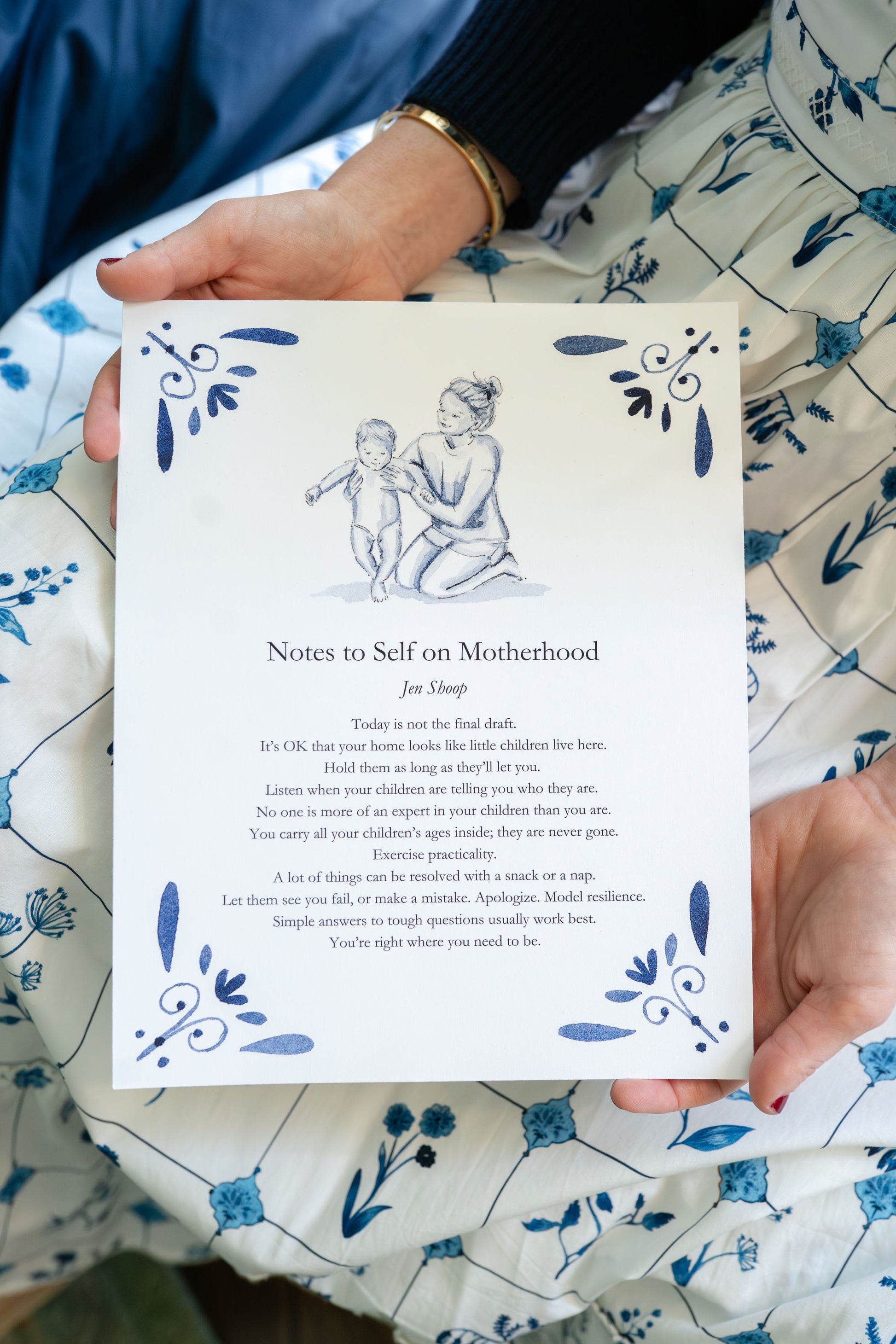 Person holding the ‘Notes to Self on Motherhood’ blue-and-white art print by Riley Sheehey with prose by Jen Shoop.