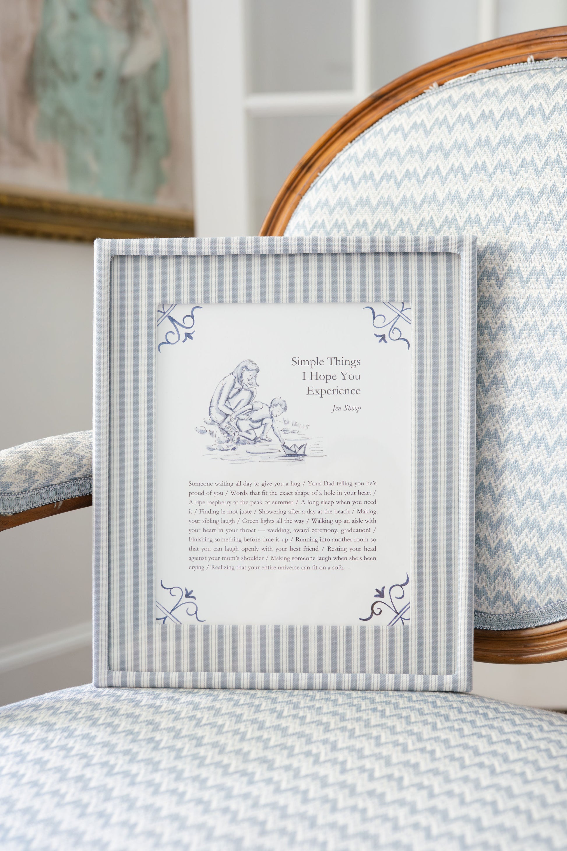 Simple Things art print framed in blue striped frame on a chair, blue-and-white decor.