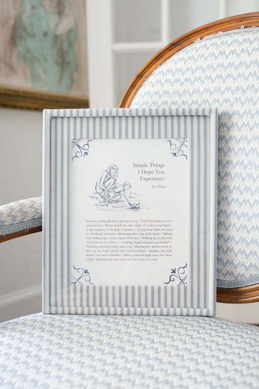 Simple Things art print framed in blue striped frame on a chair, blue-and-white decor.